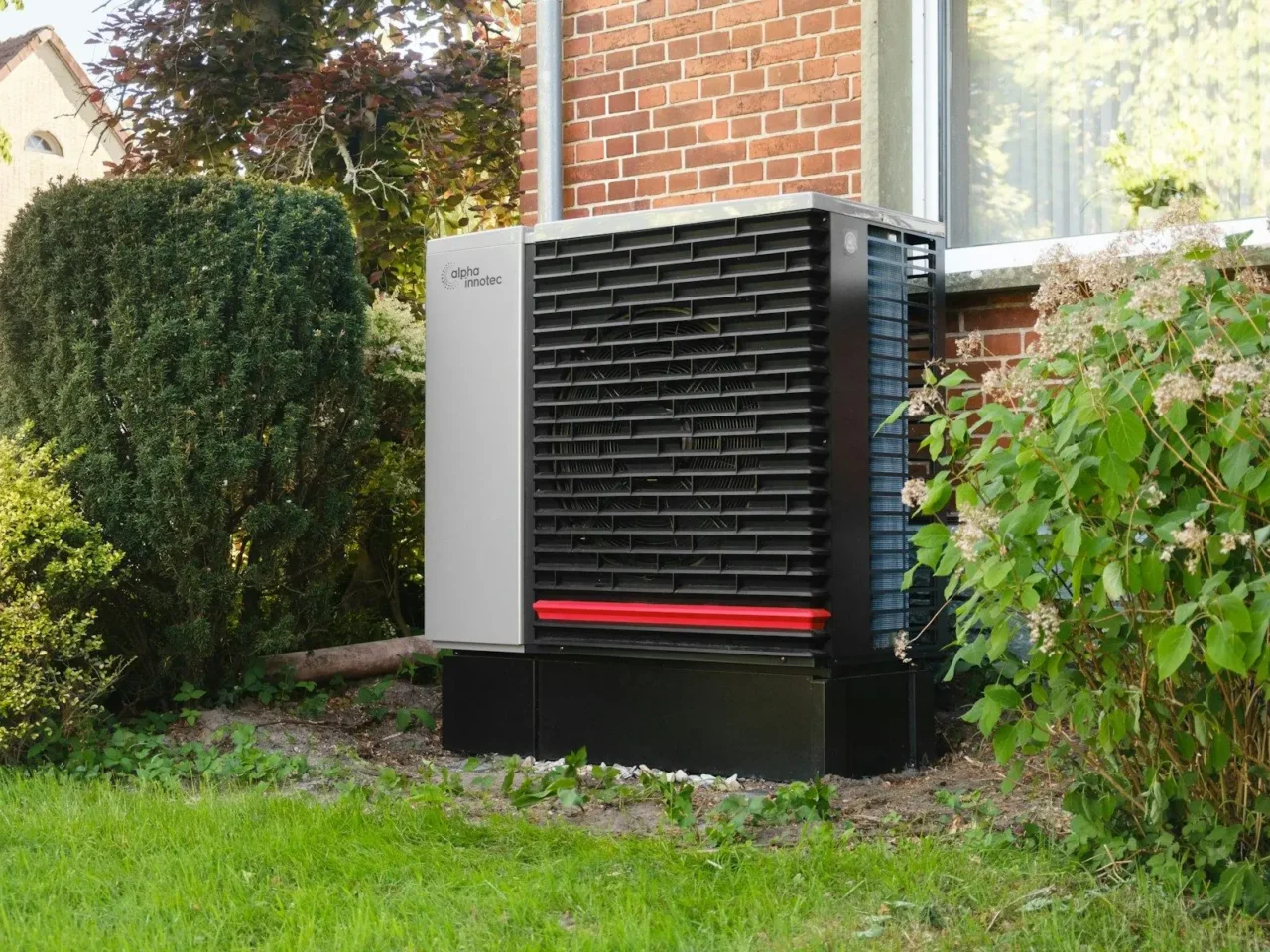 Outdoor heat pump unit installed beside a brick home