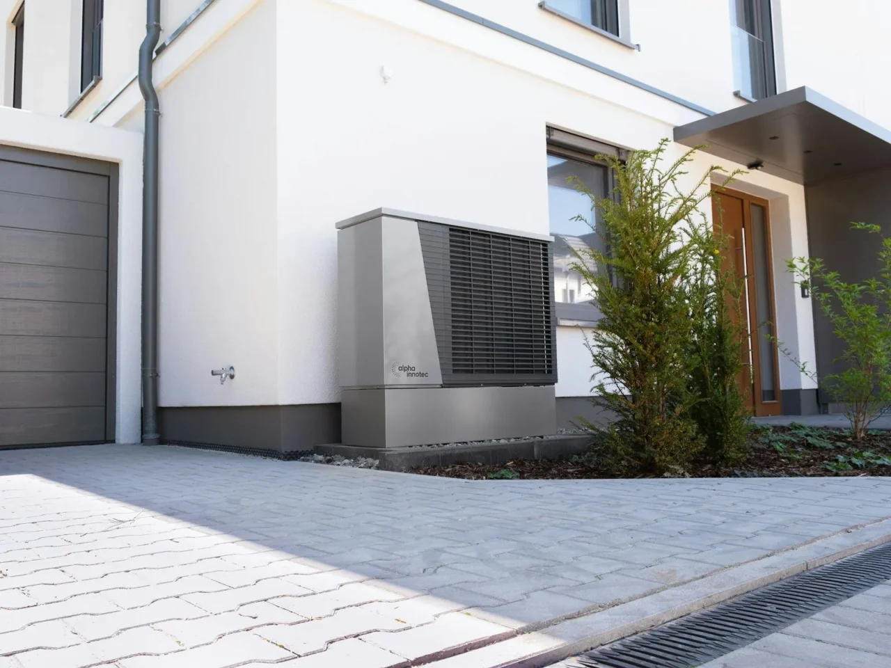 Heat pump outdoor unit beside a home driveway