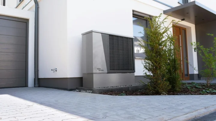 Heat pump outdoor unit beside a home driveway
